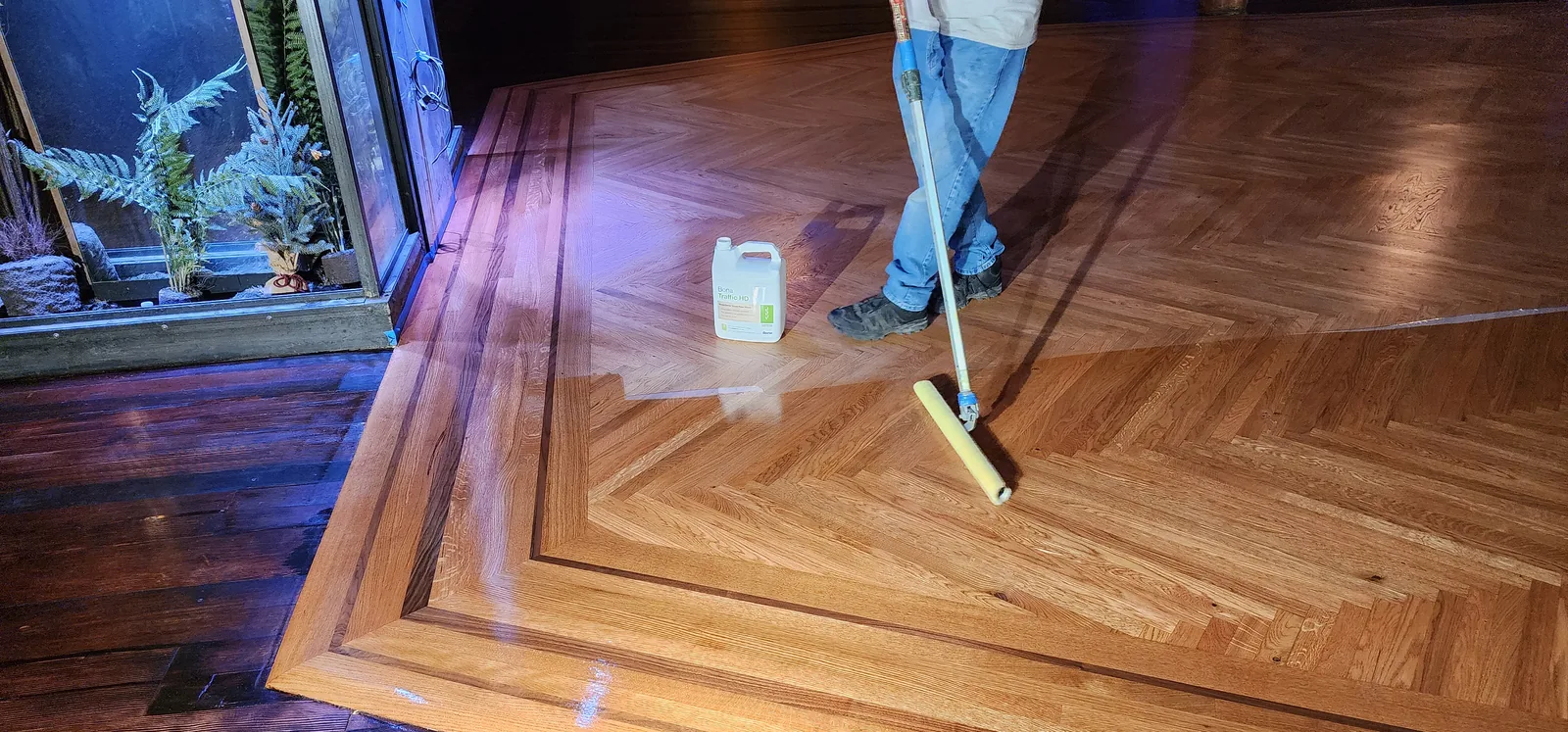 Hand-applying finish across chevron parquet flooring