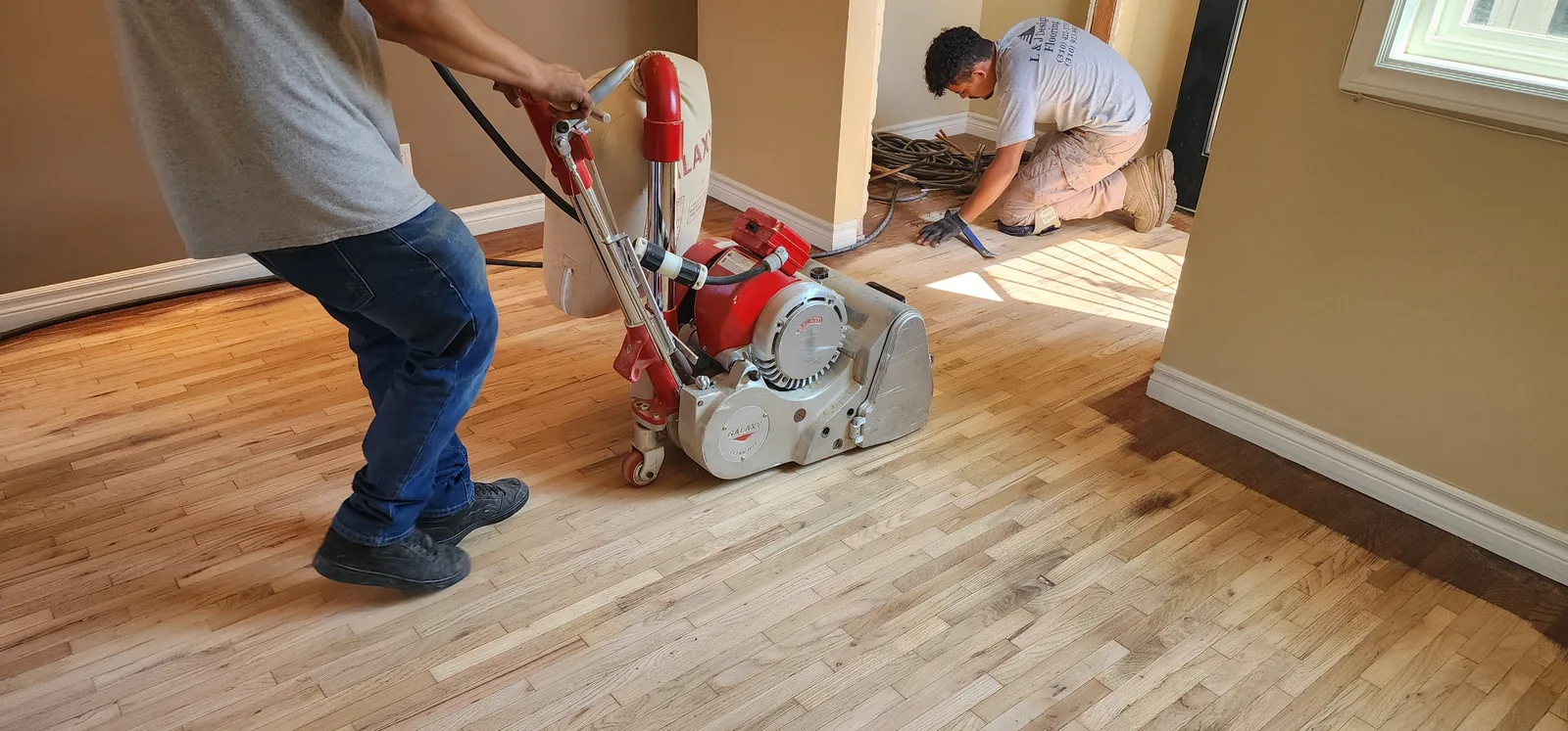 Two-man crew sanding a golden oak floor