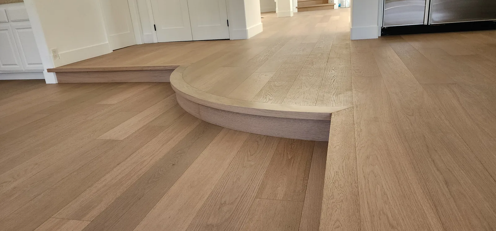 Curved raised platform edge in white oak flooring