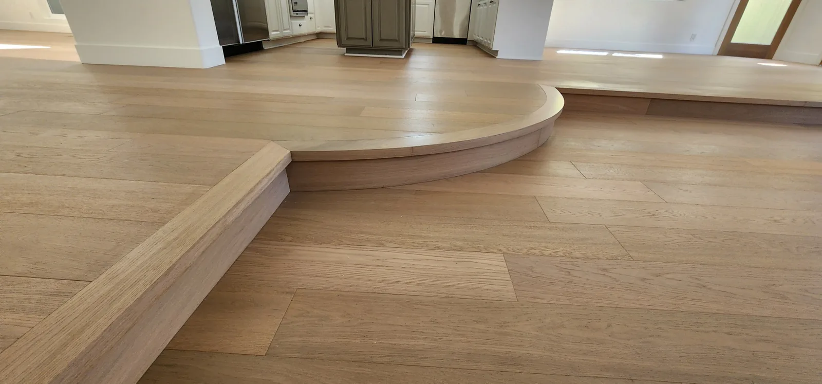 Wide view of a curved white oak platform in an open room