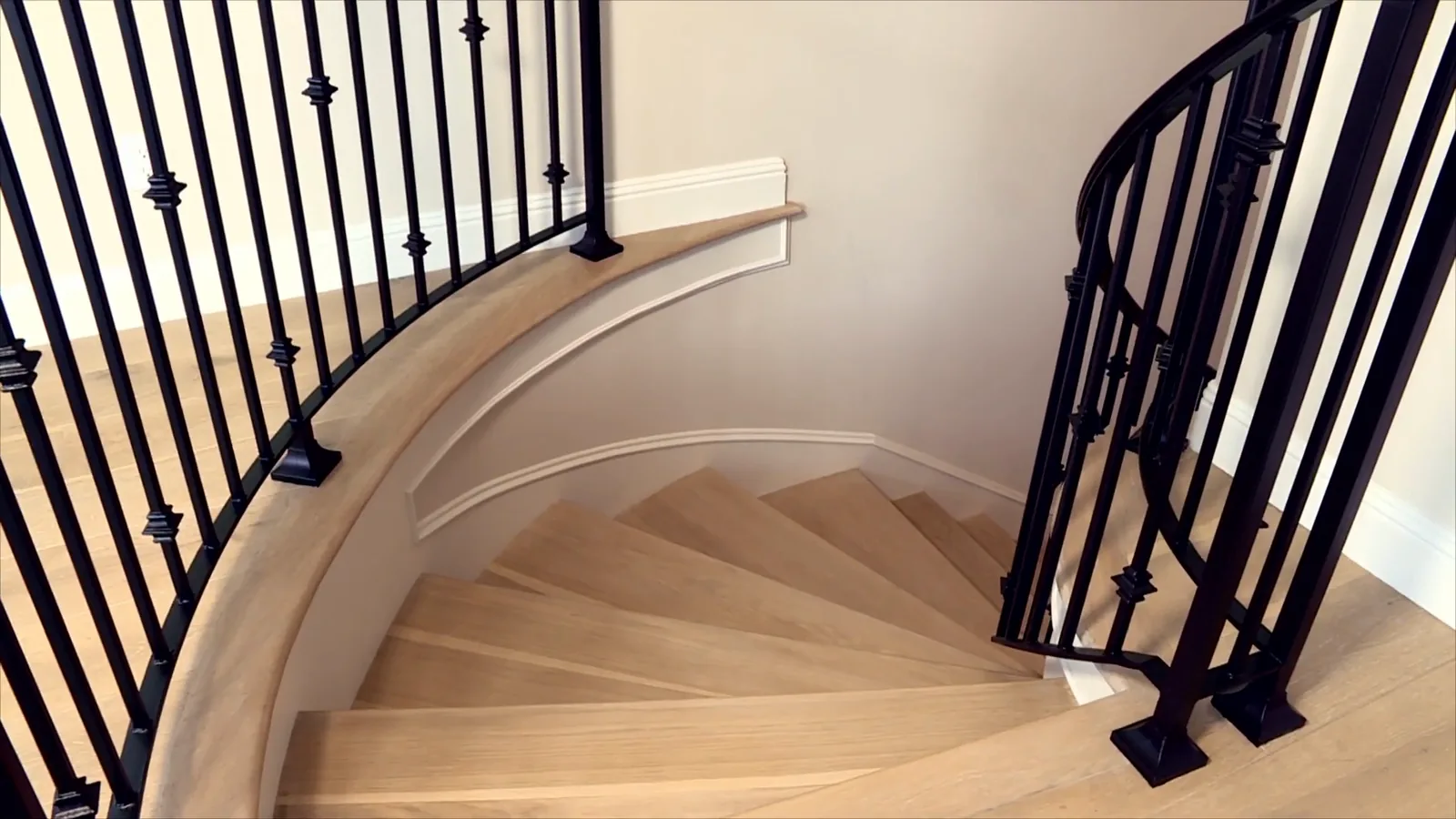Iron balusters on a curved white oak staircase