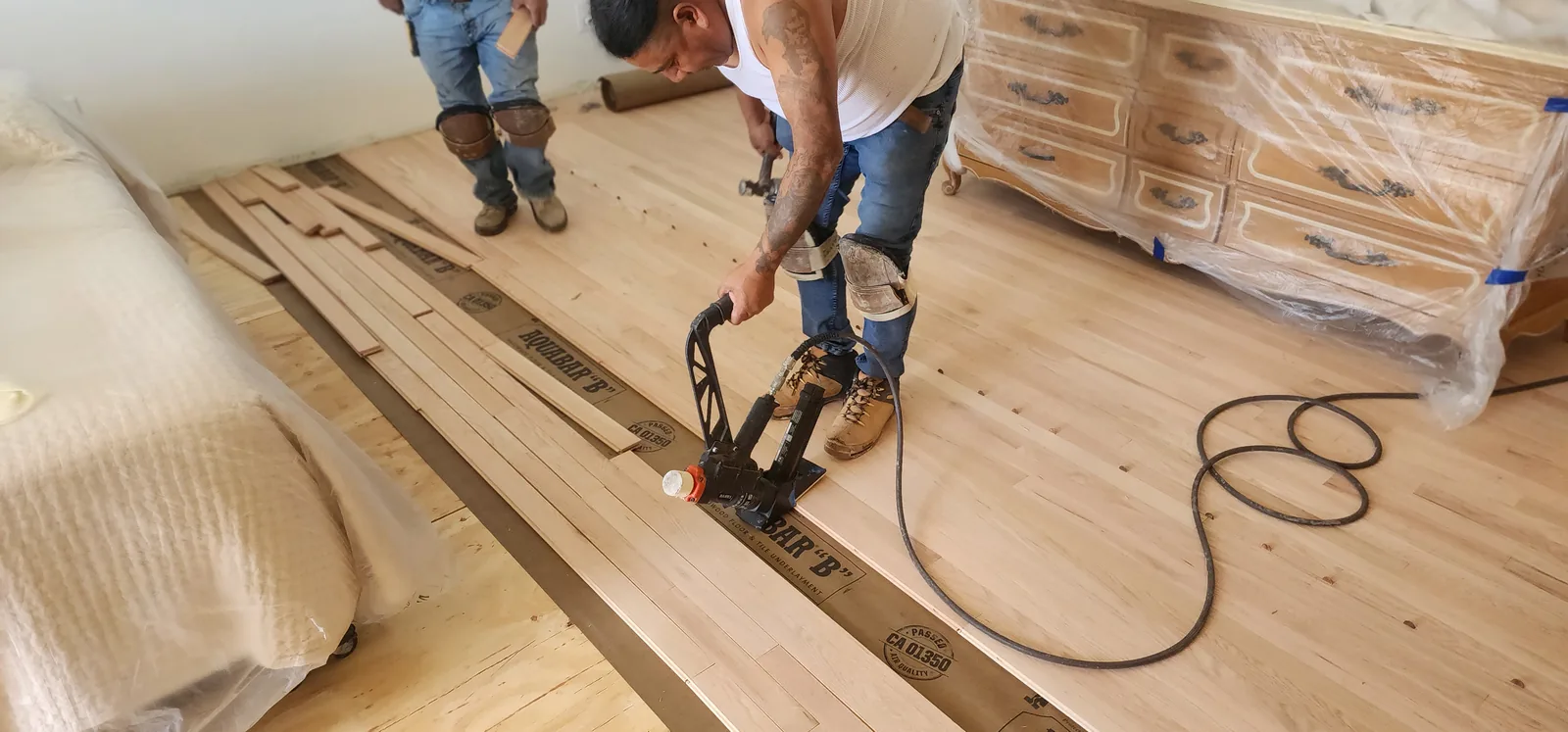 Paul's crew fastening hardwood planks with a pneumatic flooring nailer